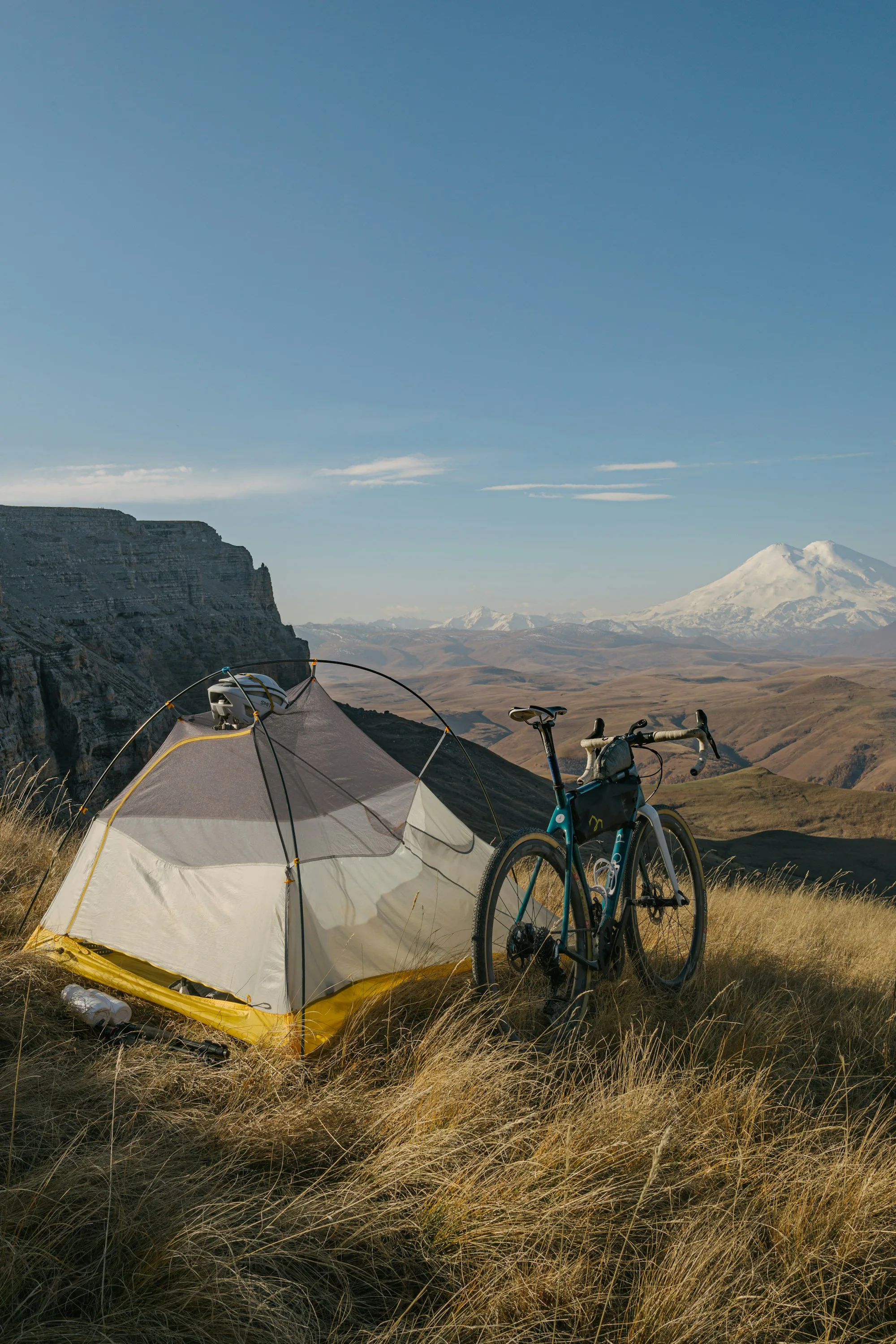 A gravel bike parked beside a tent on a high plateau
