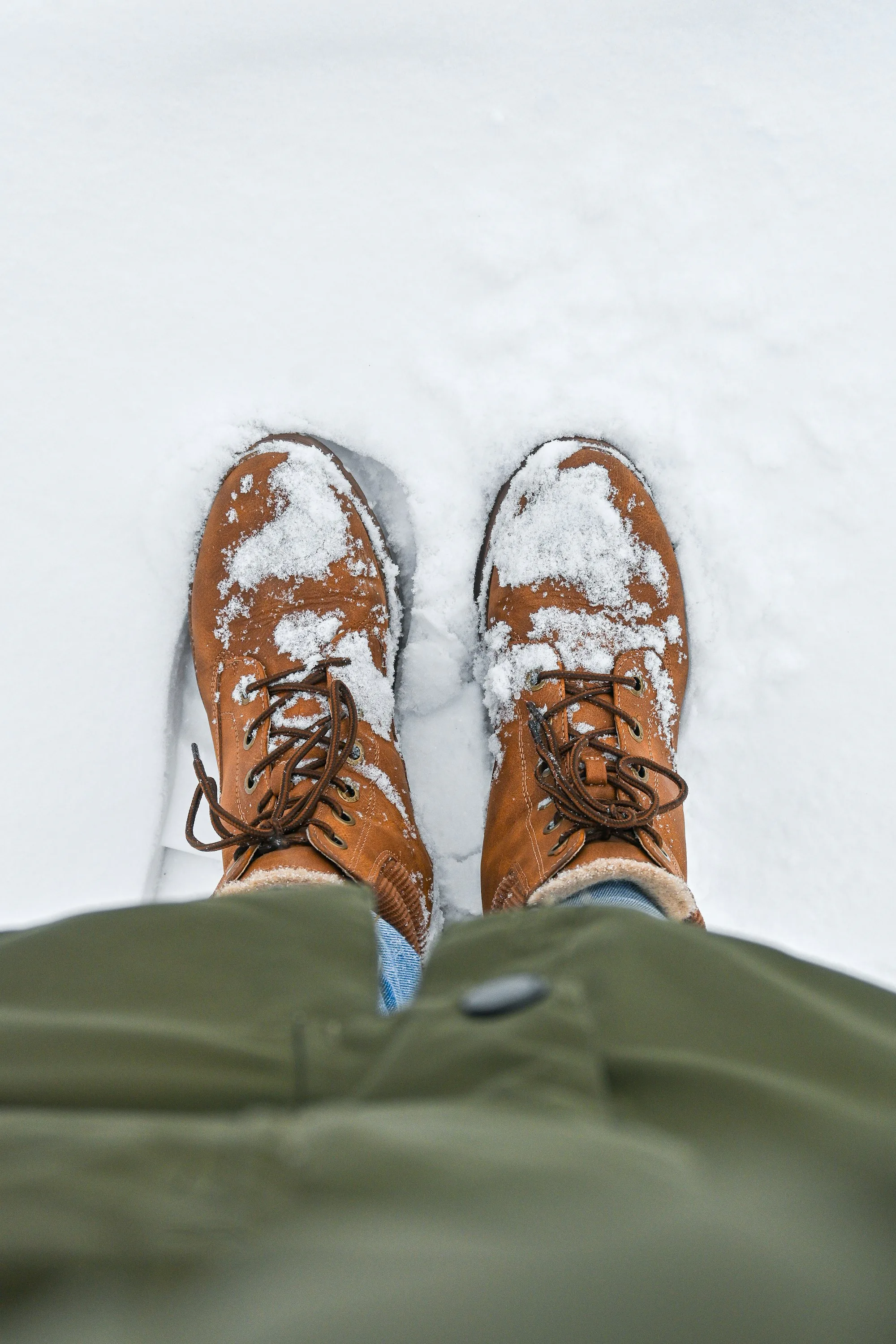 Brown boots dusted with snow, seen from above