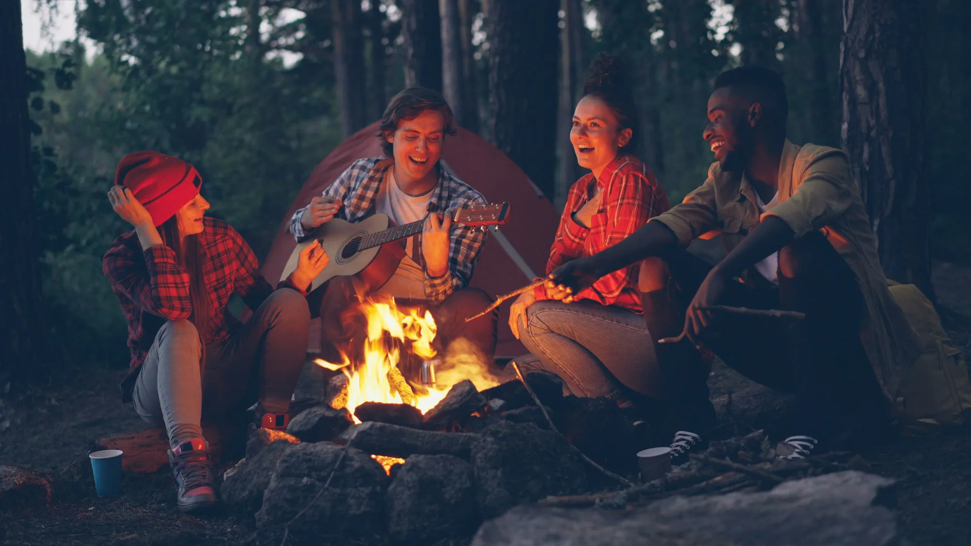 Friends laughing around a campfire in the woods