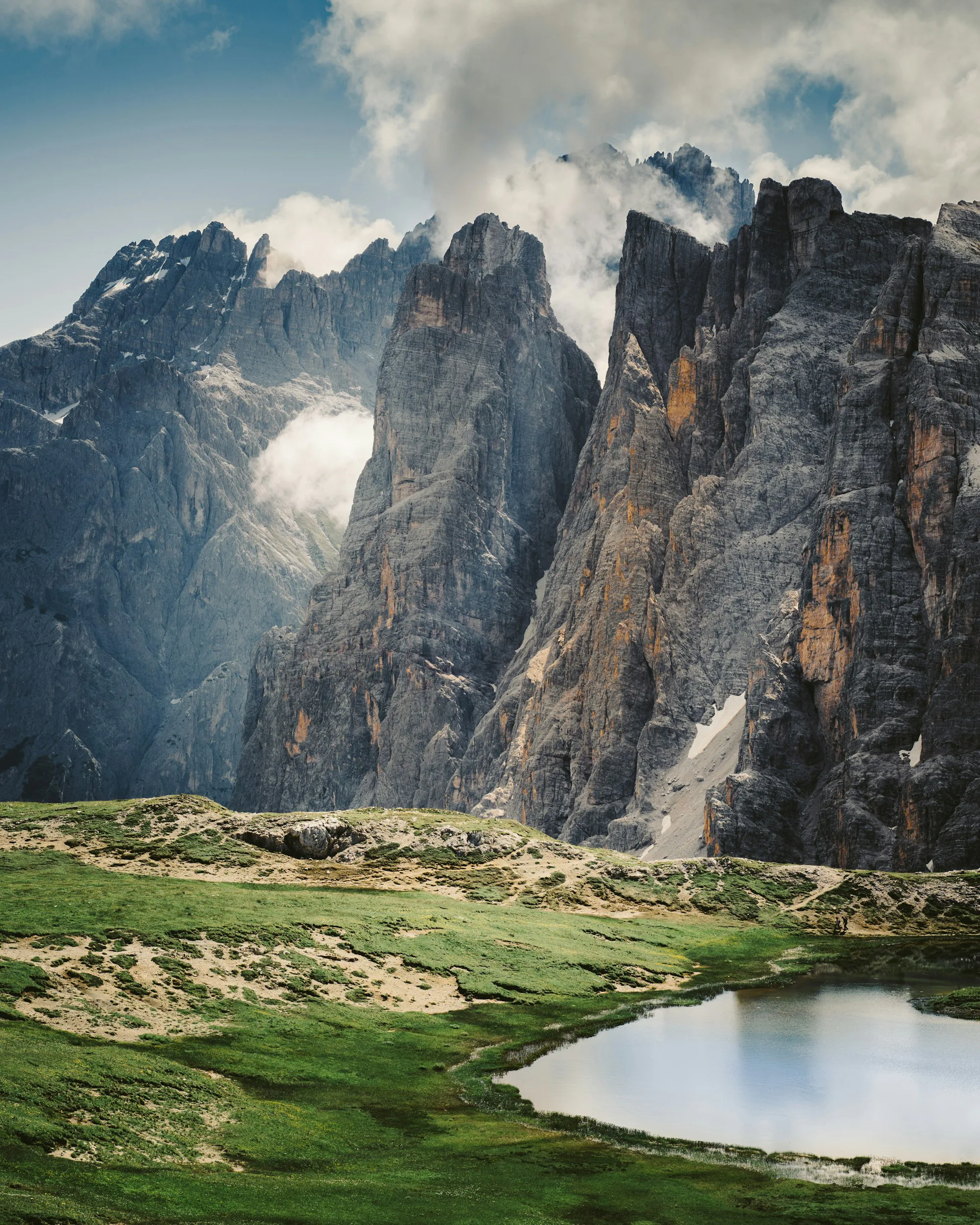 A green meadow below a rocky mountain in the Dolomites