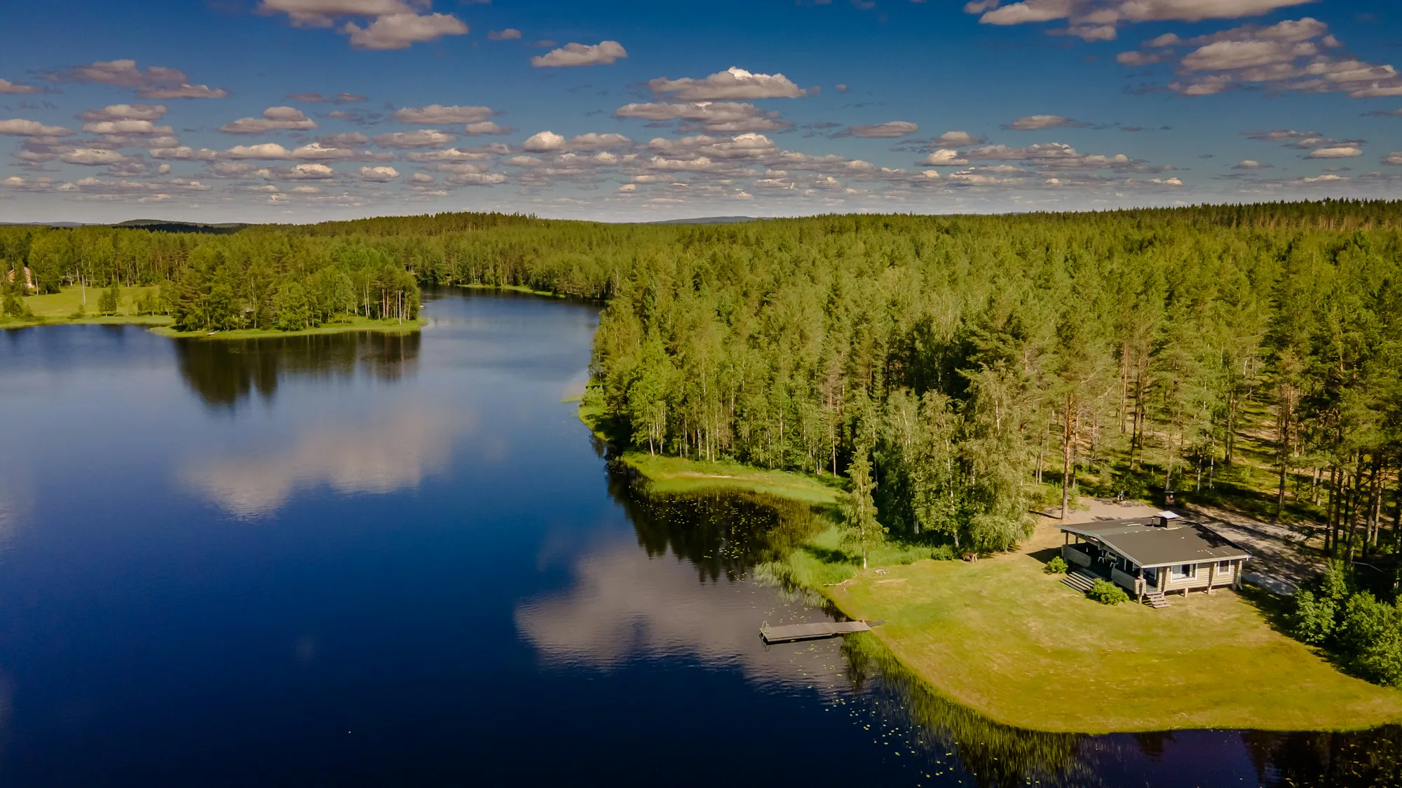 A forest lake and a lakeside cabin seen from above
