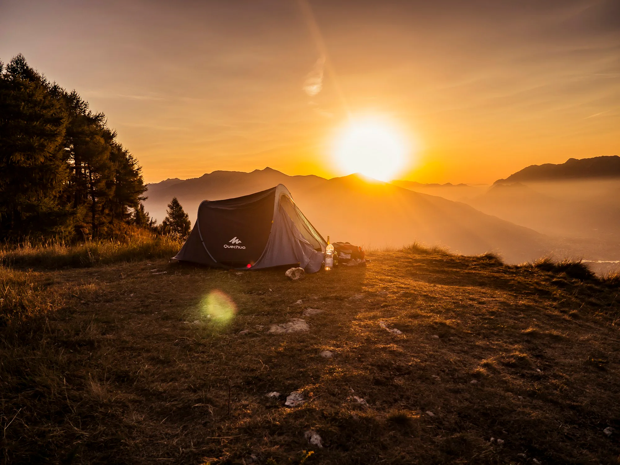 A tent on a mountain top as the sun sets