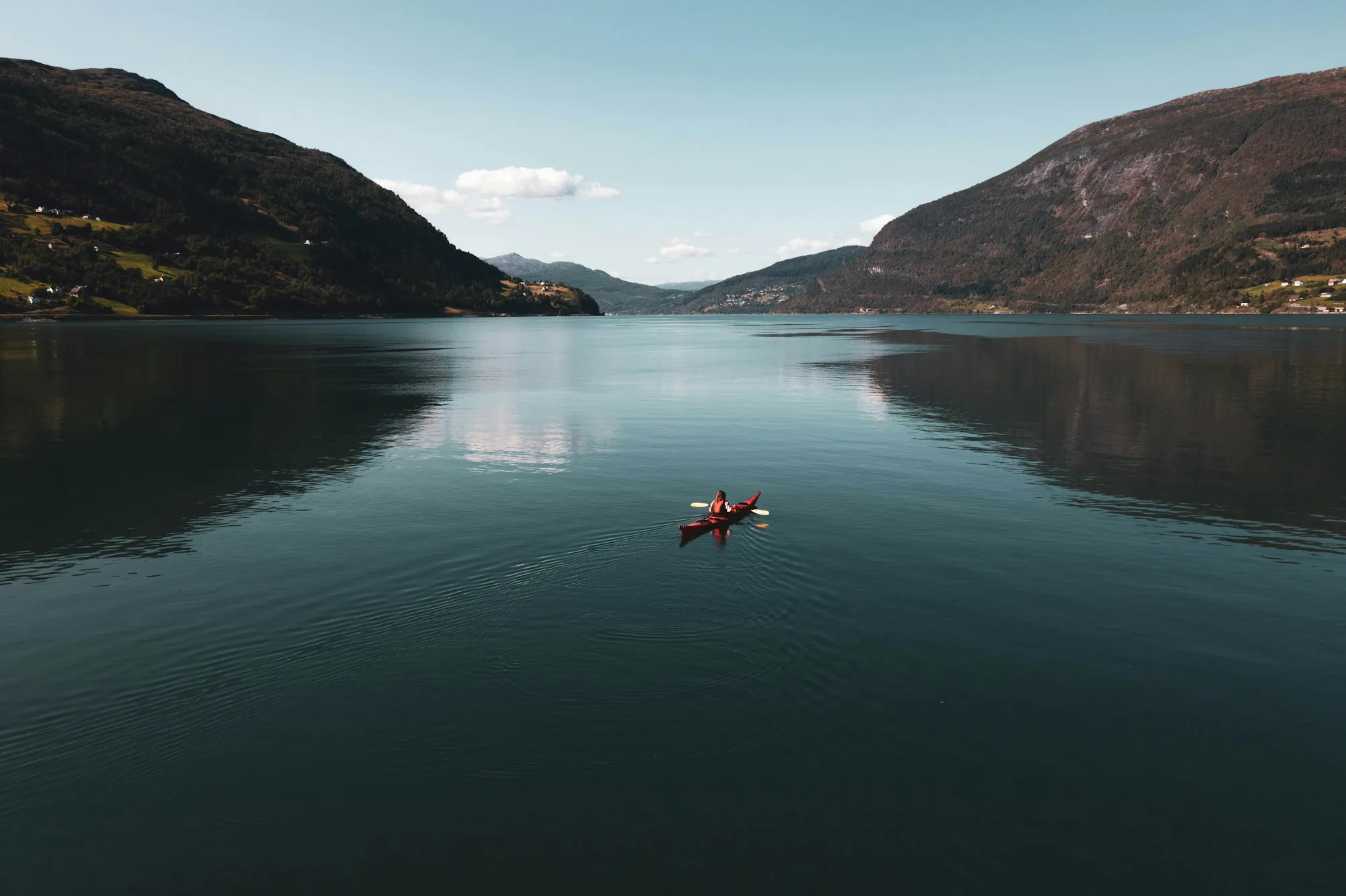 A lone kayak on a still, mirror-like lake