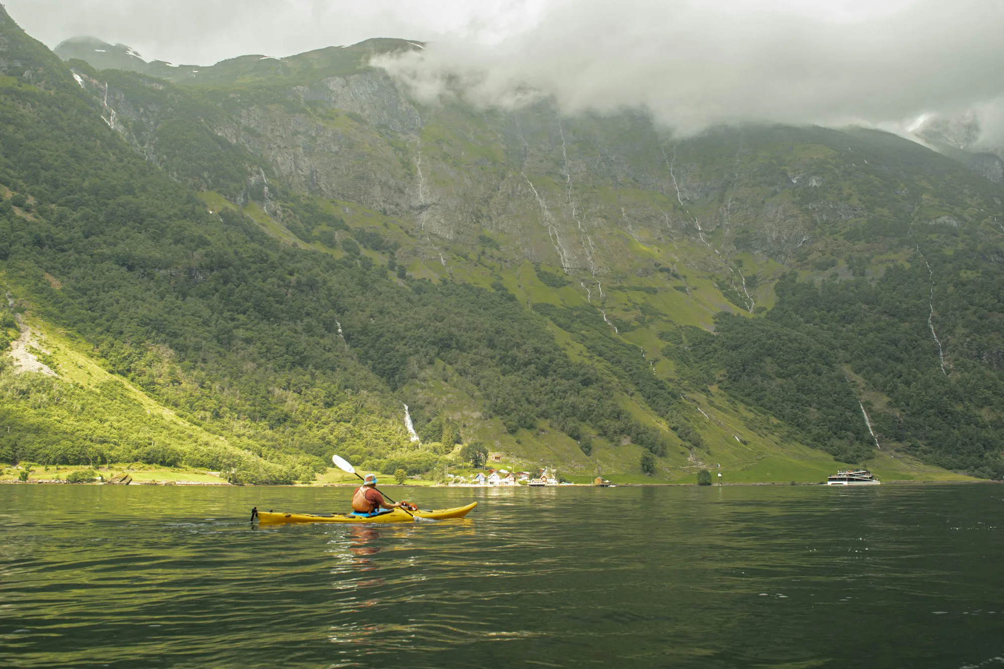 A paddler in a canoe on a lake with mountains behind