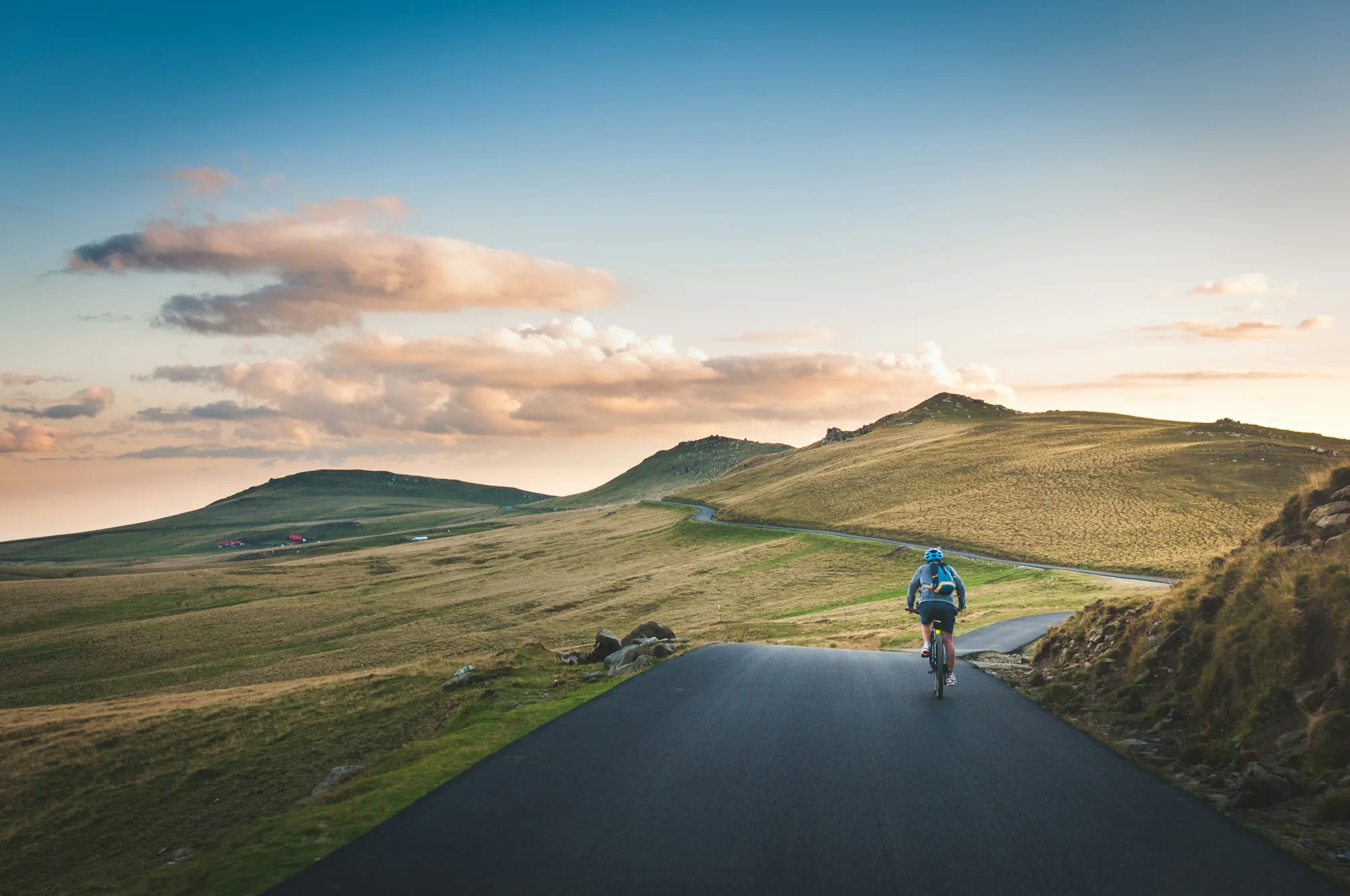 A cyclist on a long road towards mountains