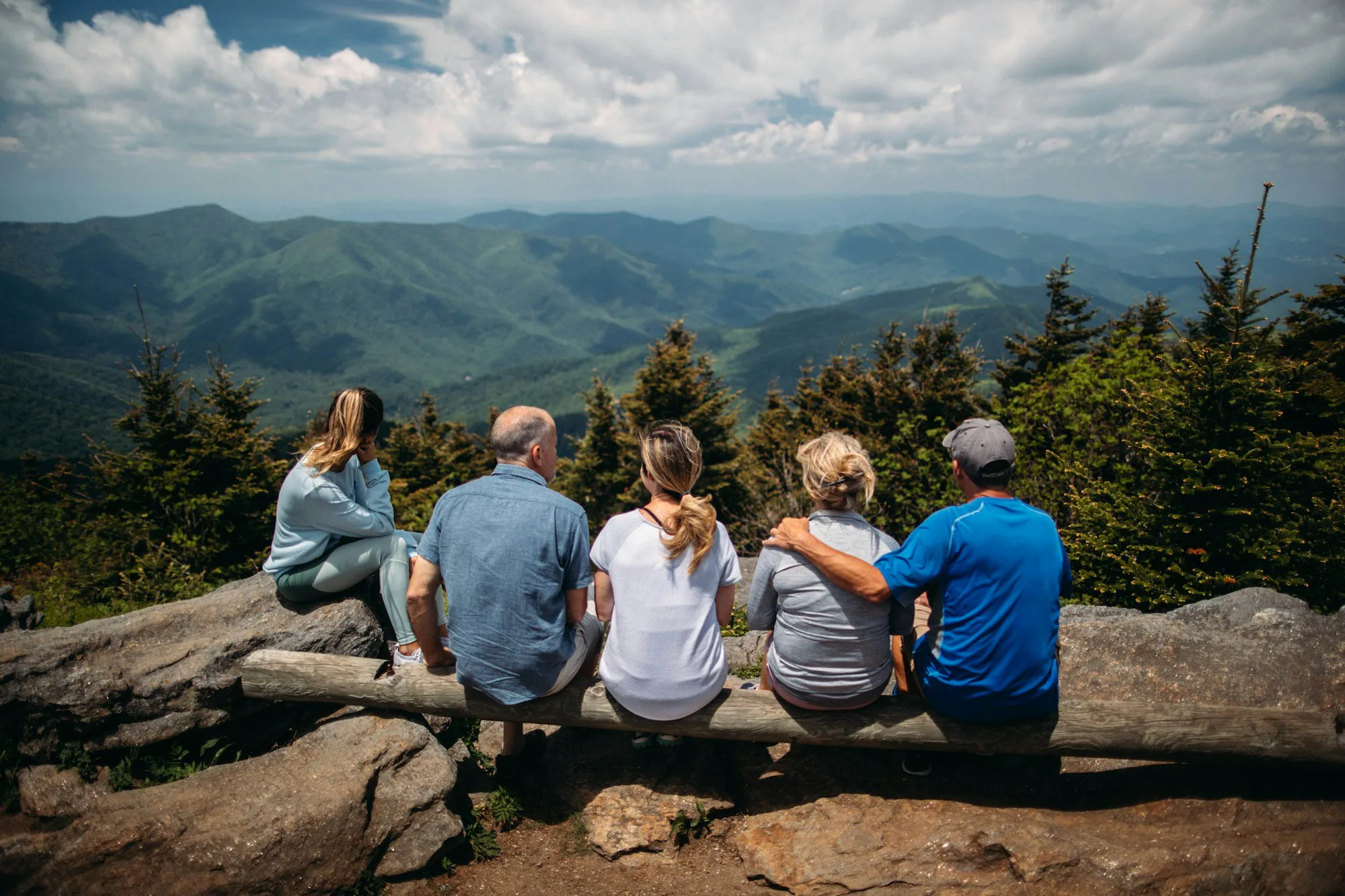 A group of hikers resting on rocks above a mountain valley