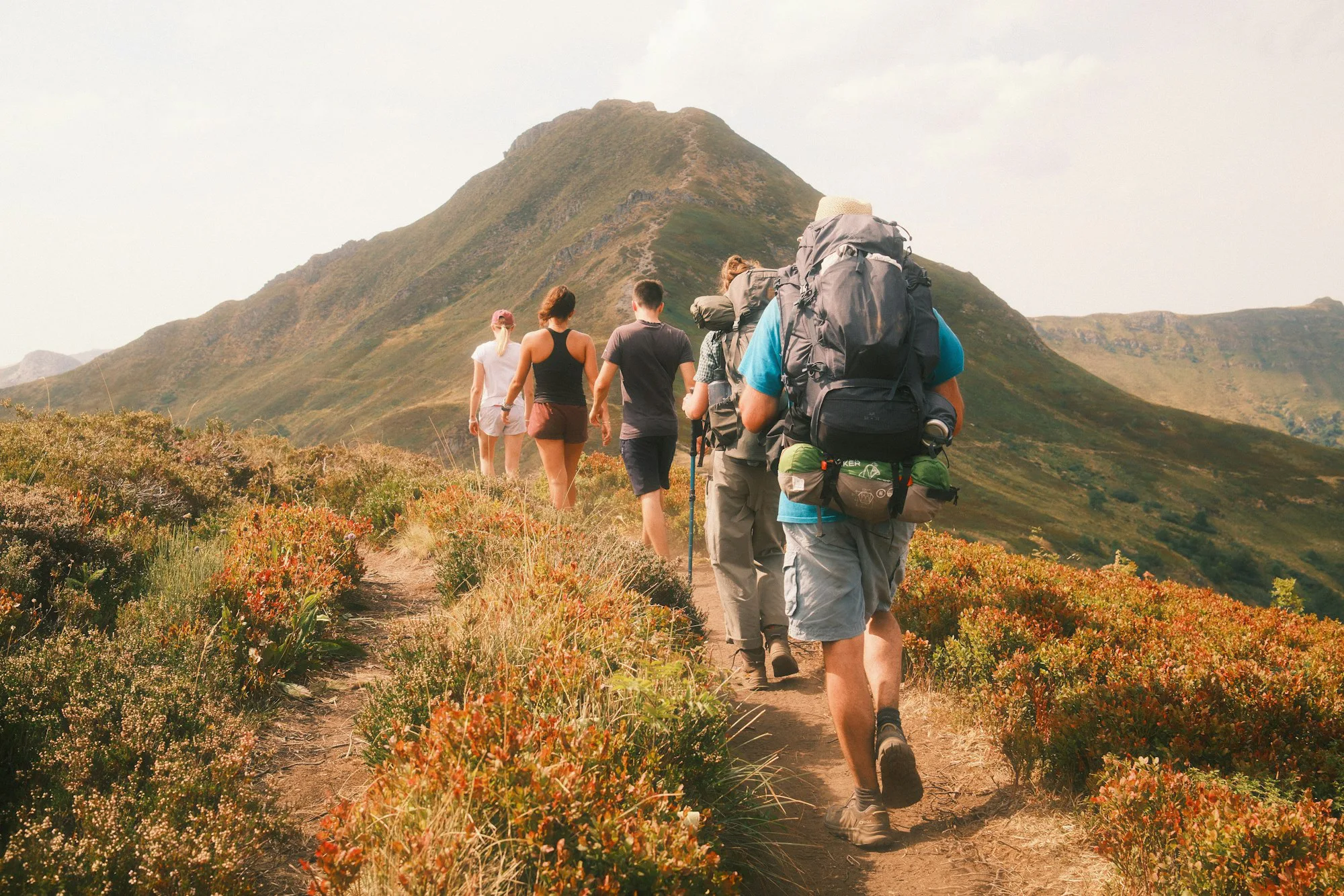 A group hiking on a trail towards a large mountain peak