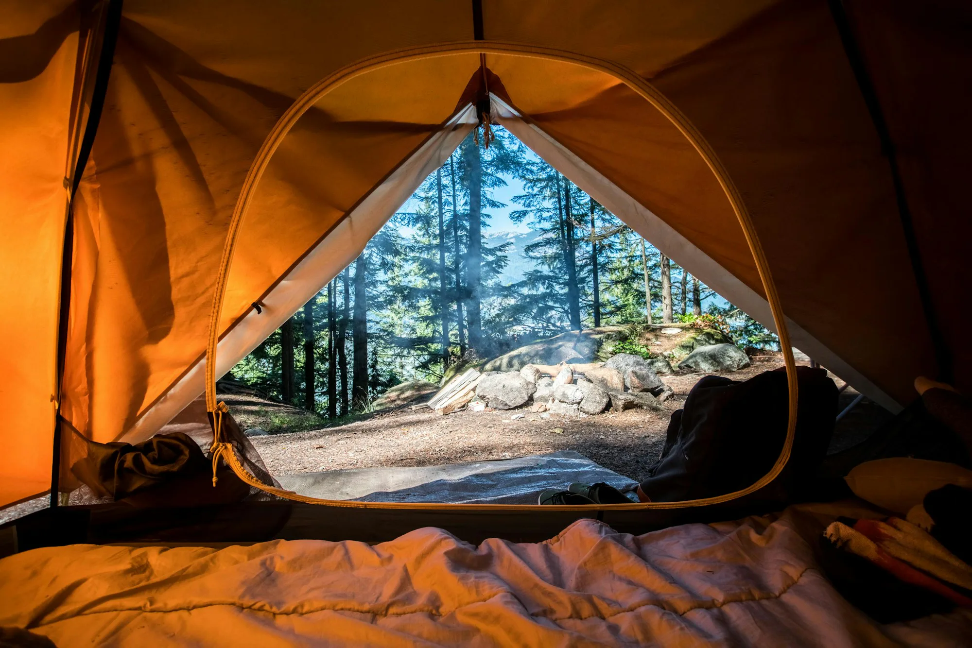 An orange tent pitched among trees