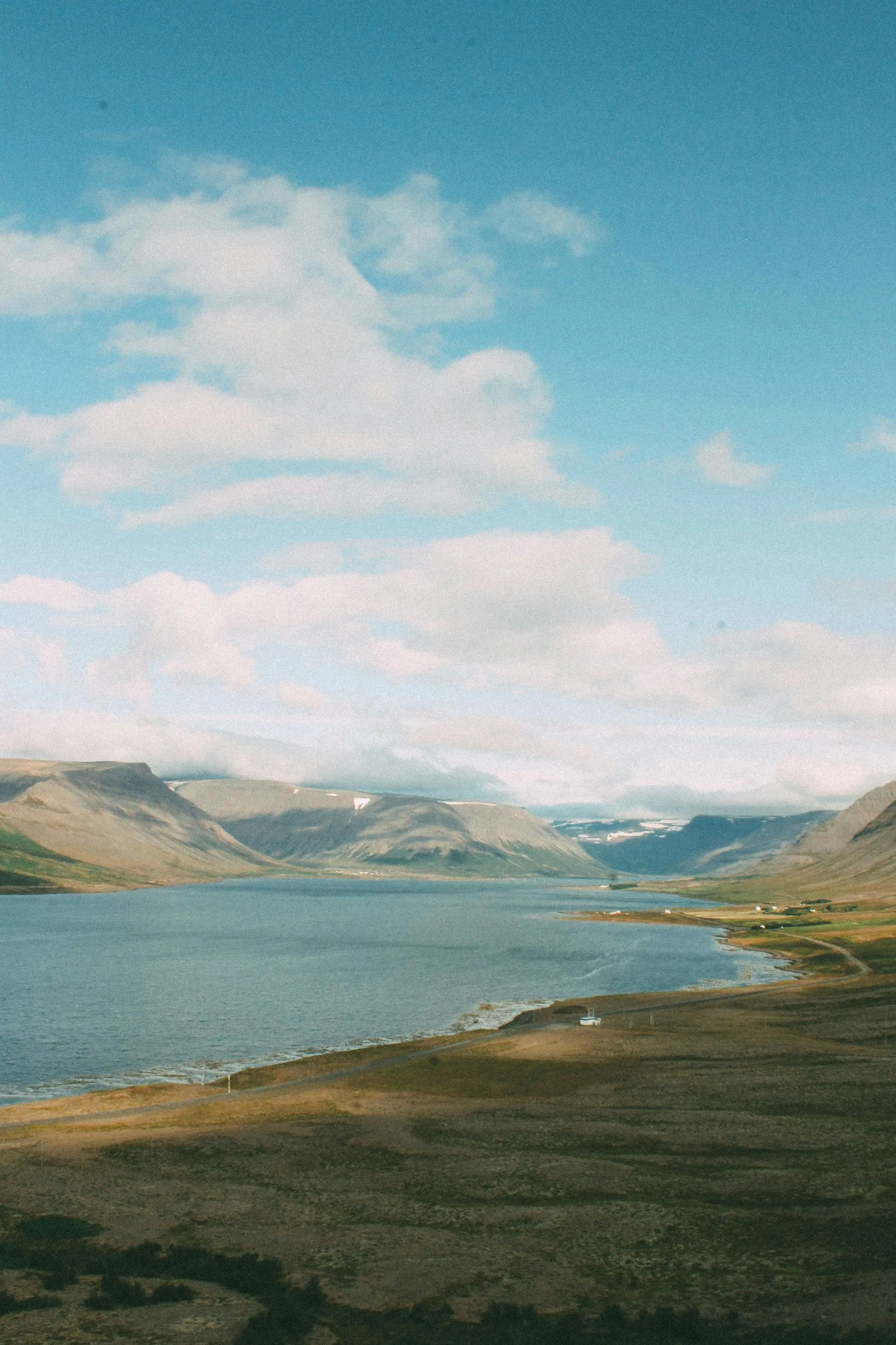 A wide fjord and green valley under a soft blue sky
