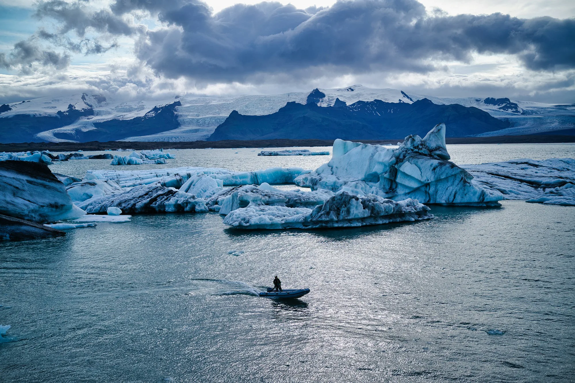 A lone kayaker among icebergs on a glacier lagoon