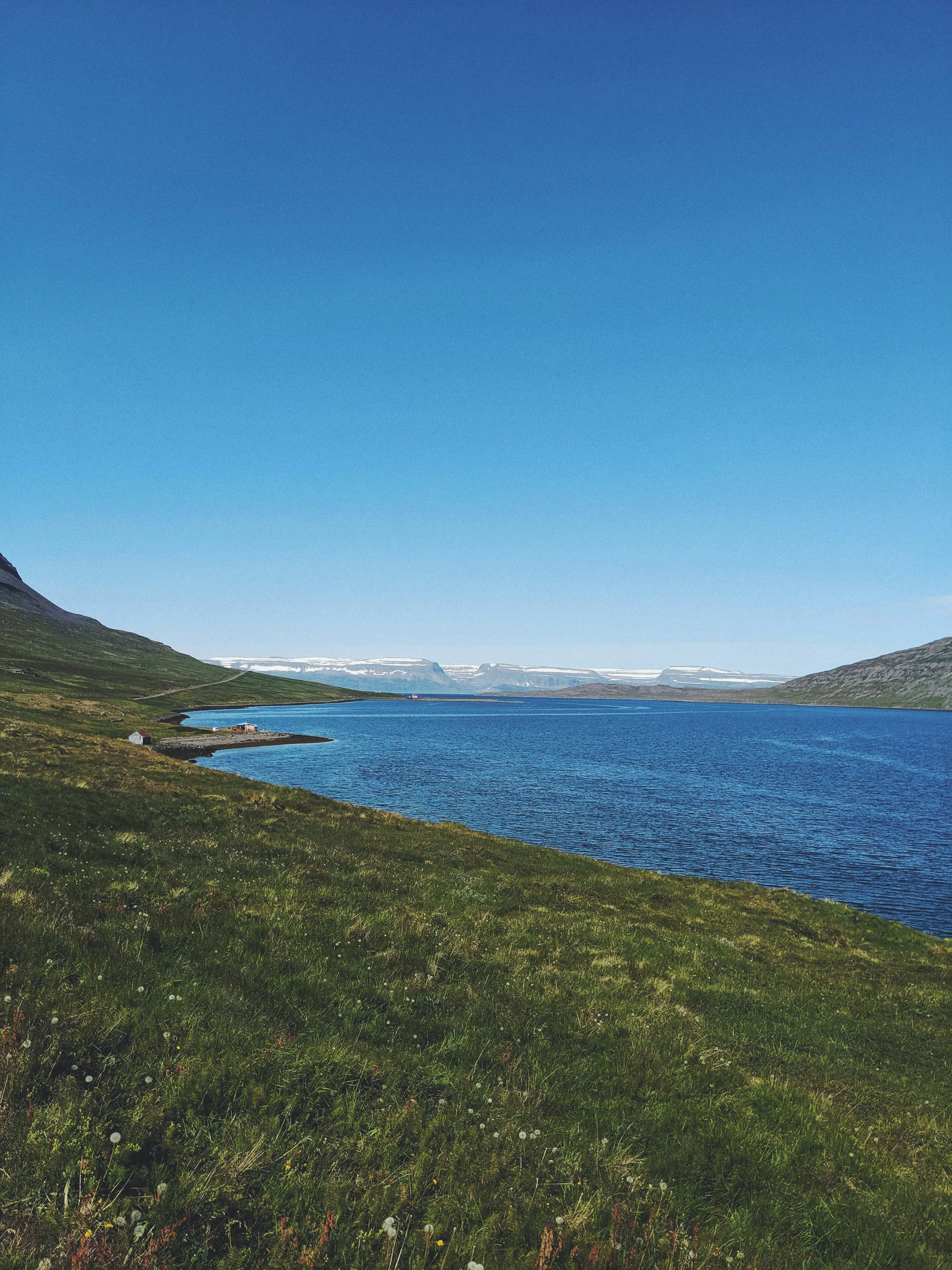 A blue lake below green hills in Iceland