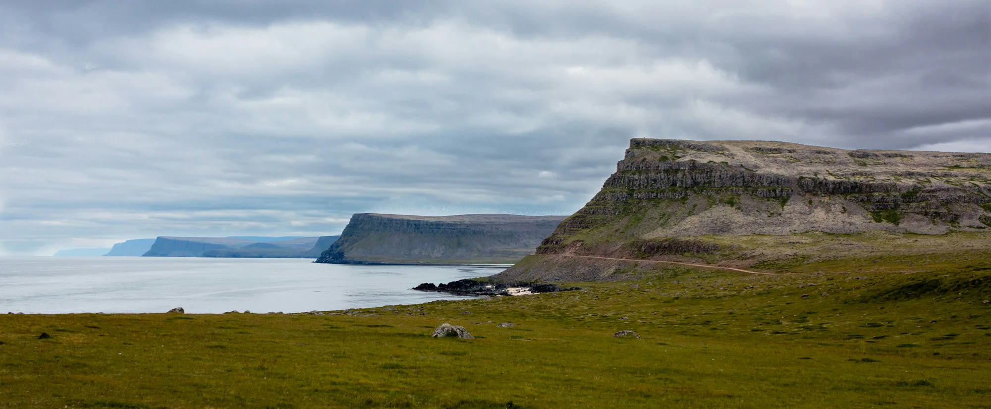 A green coastal headland and a fjord in the Westfjords