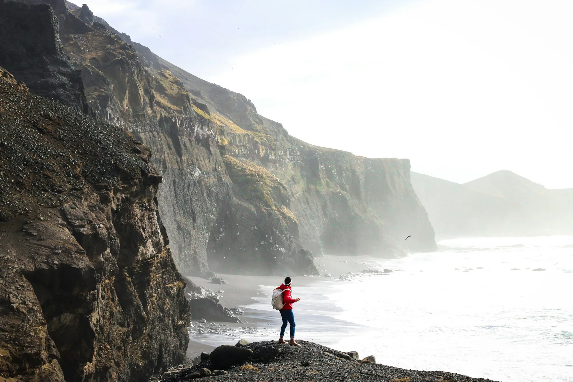 A walker on a sea cliff above crashing surf