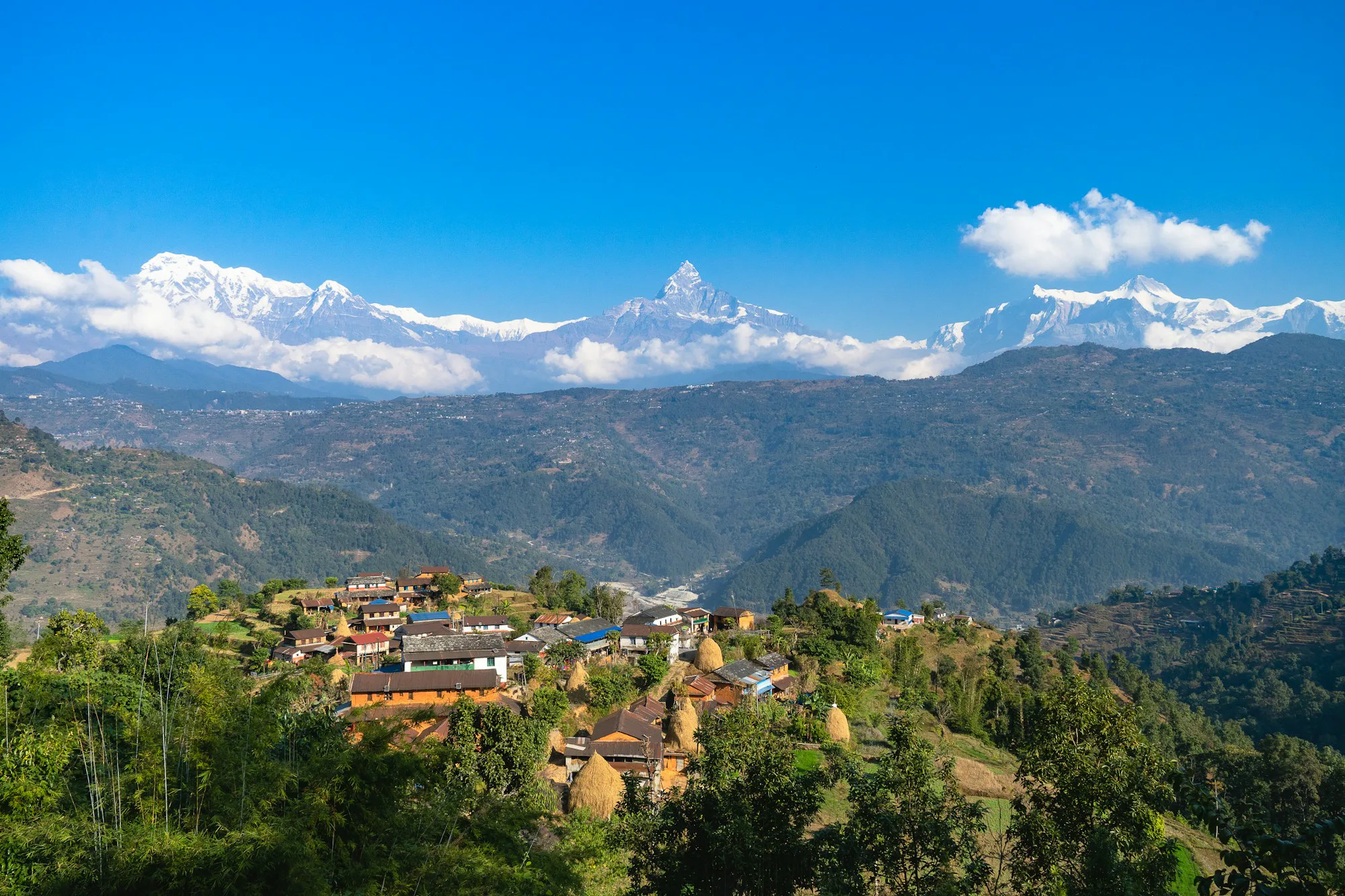 A hill village of stone houses below the snowy Annapurna range