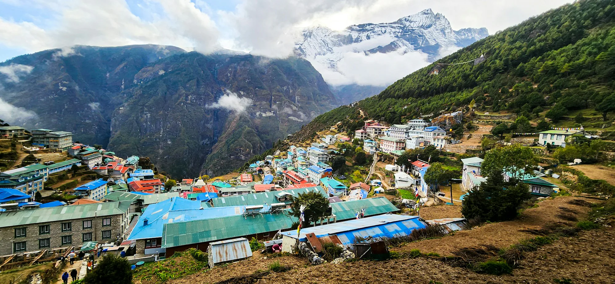 Namche Bazaar's colourful houses on a hillside below snowy peaks