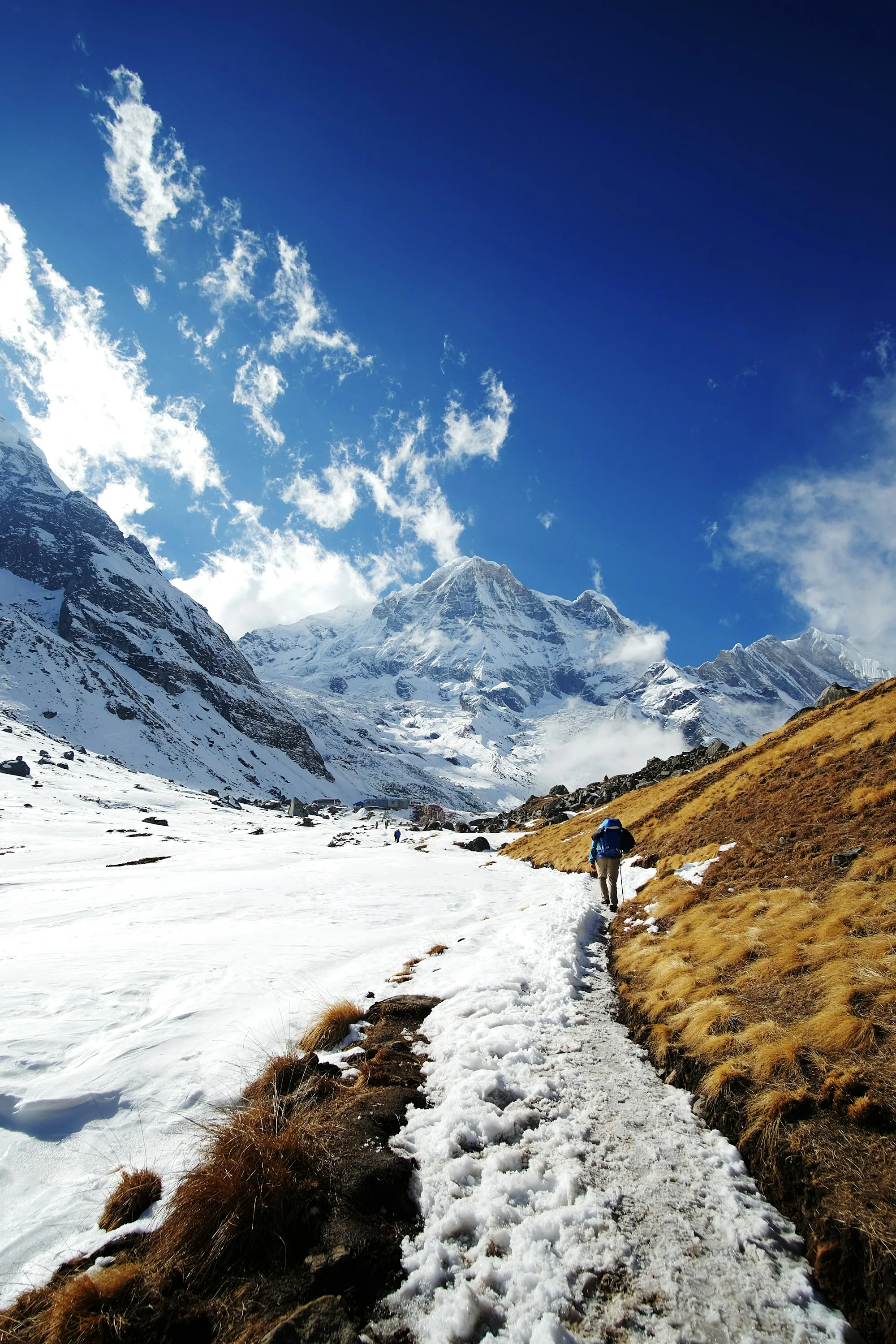 A trekker climbing a snowy slope below Himalayan peaks
