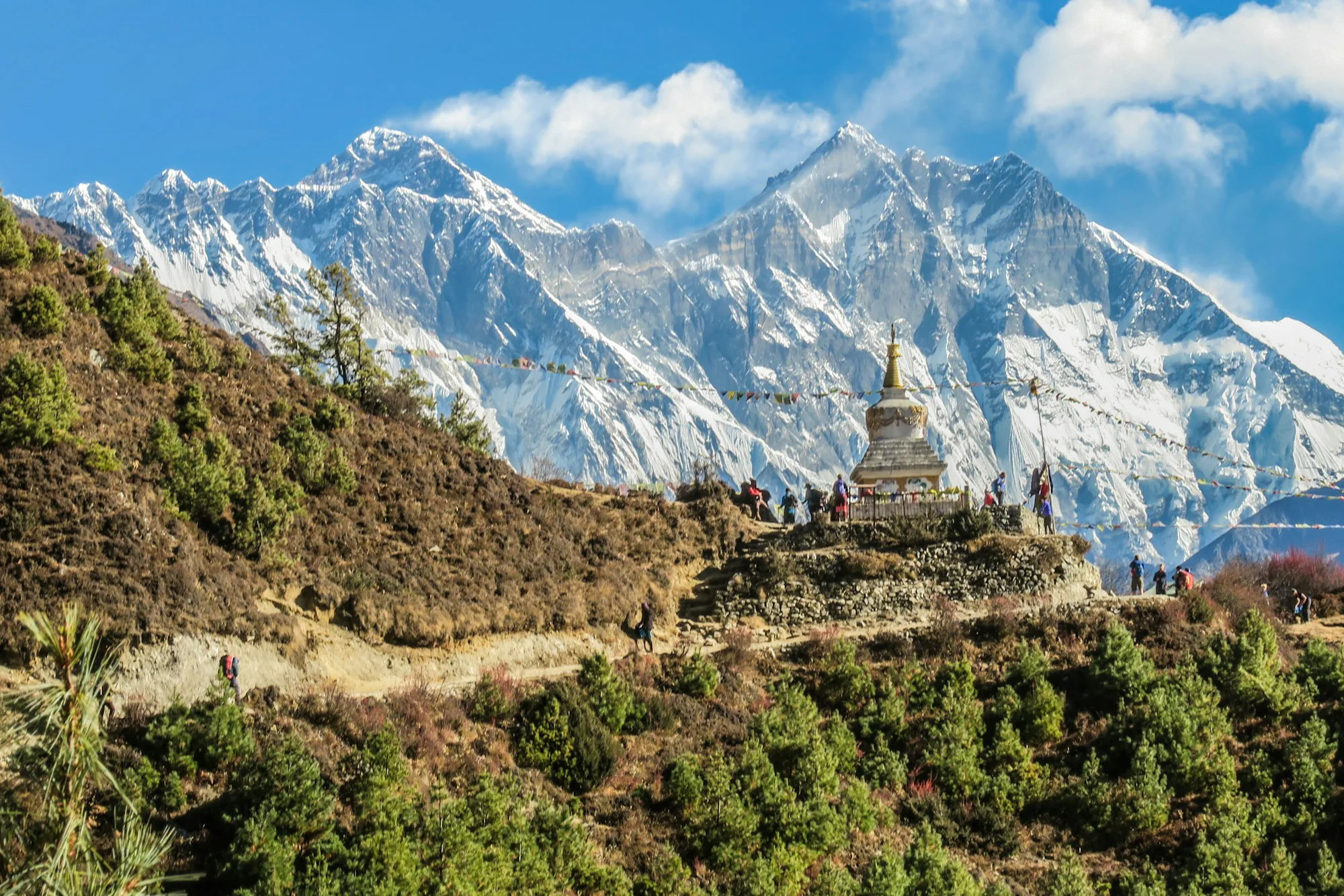A white stupa with prayer flags below the snowy peaks of the Everest region