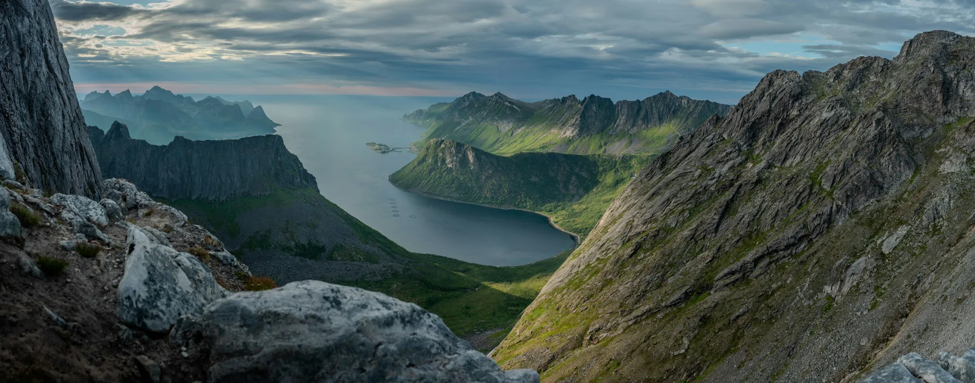 A fjord between green mountains seen from a high cliff