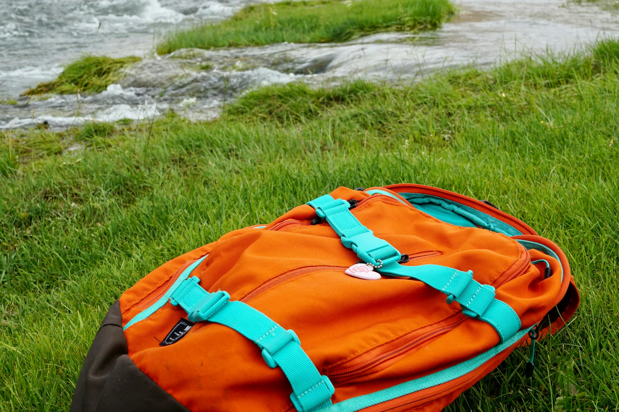 An orange and teal pack lying on green grass