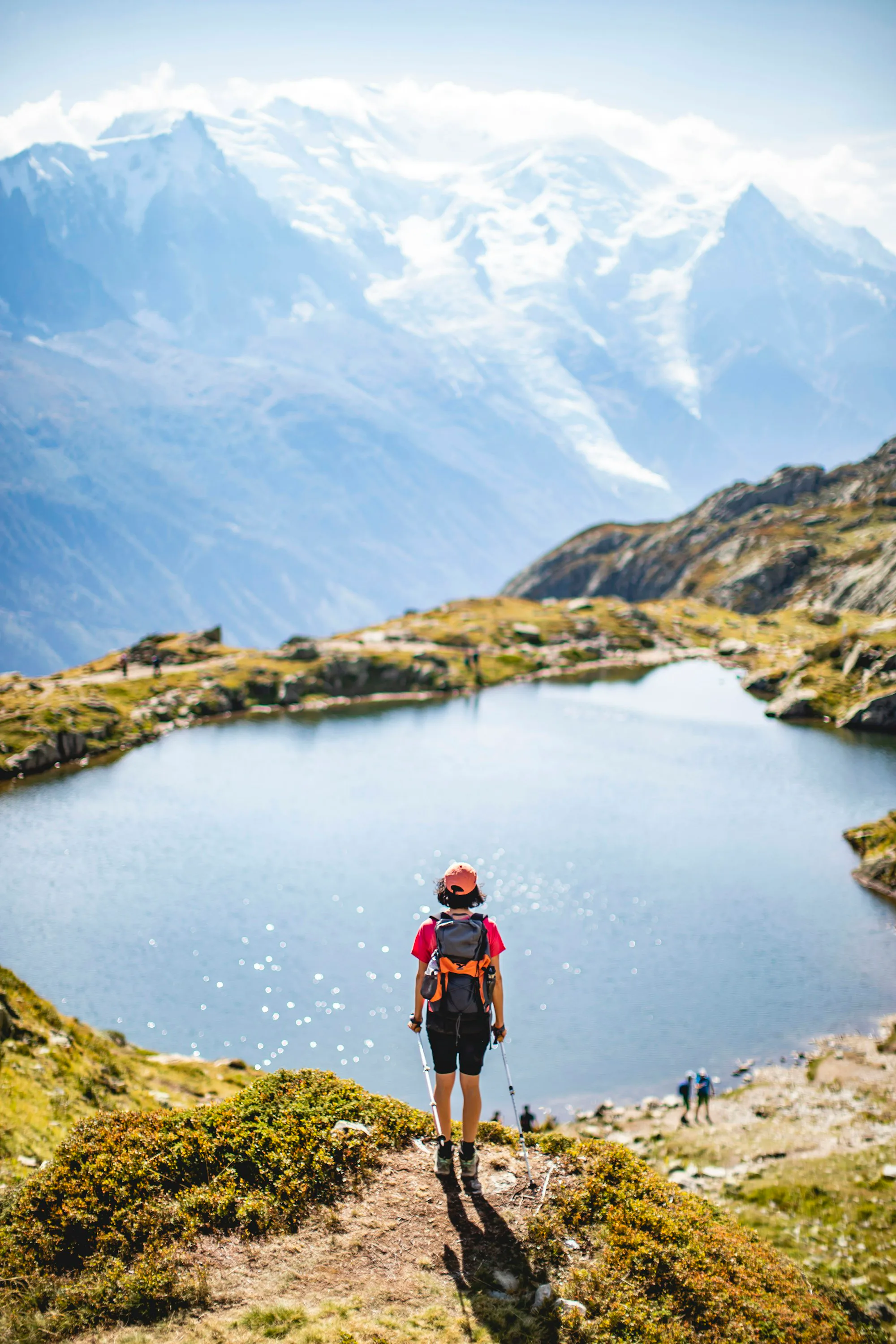 A hiker in a red jacket above a mountain lake