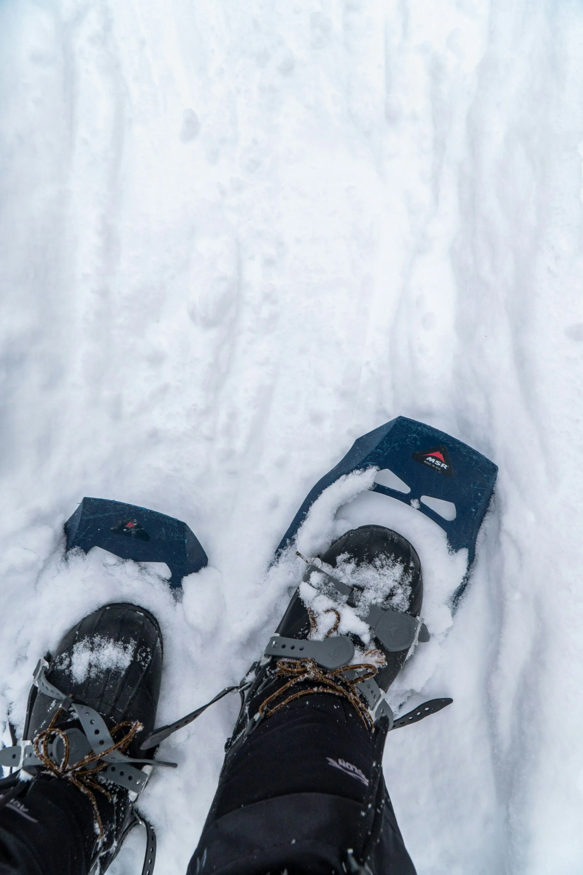 A person wearing snowshoes in deep snow