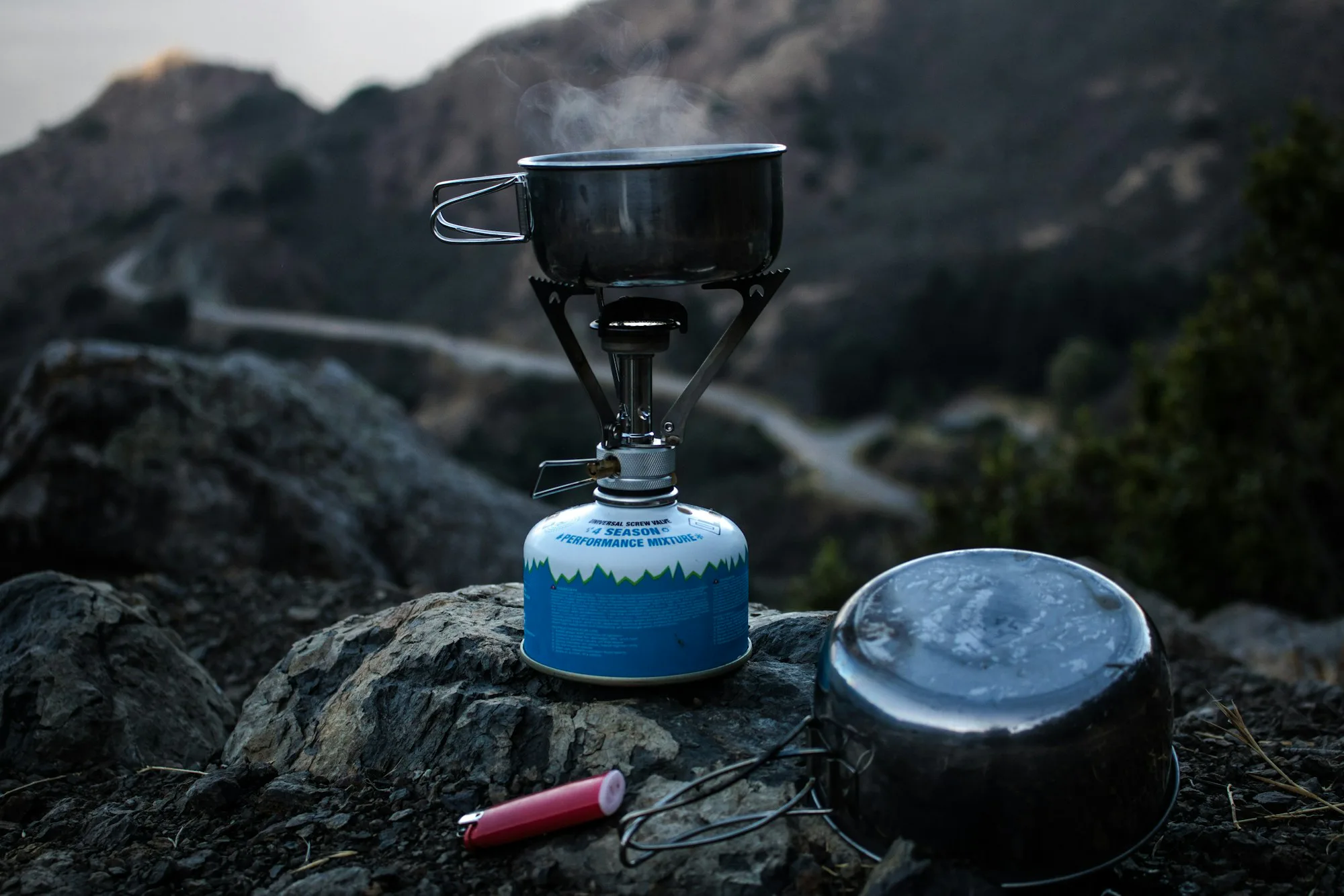 A blue gas stove and pot on a rock high in the mountains