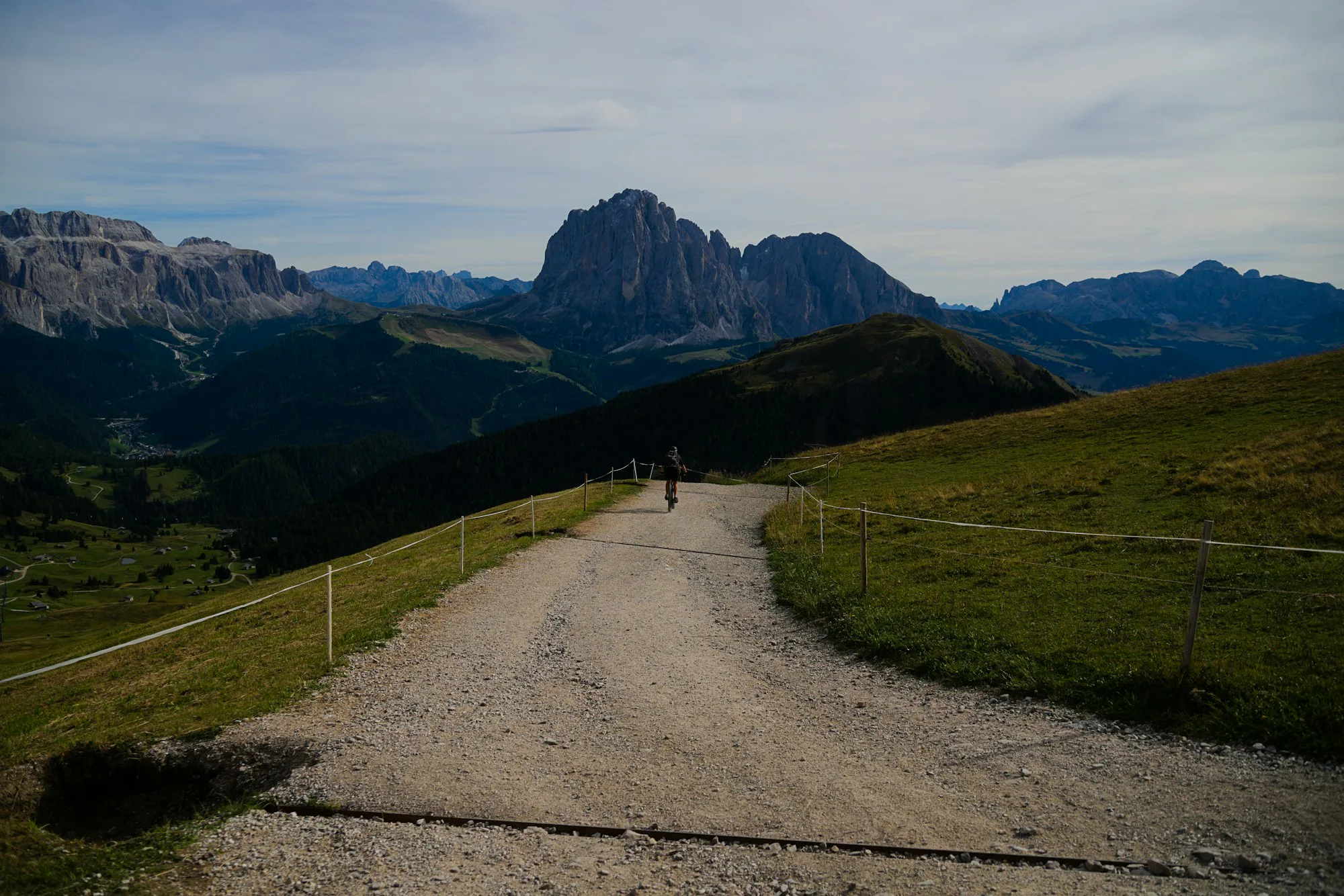 A gravel road leading towards rocky alpine peaks