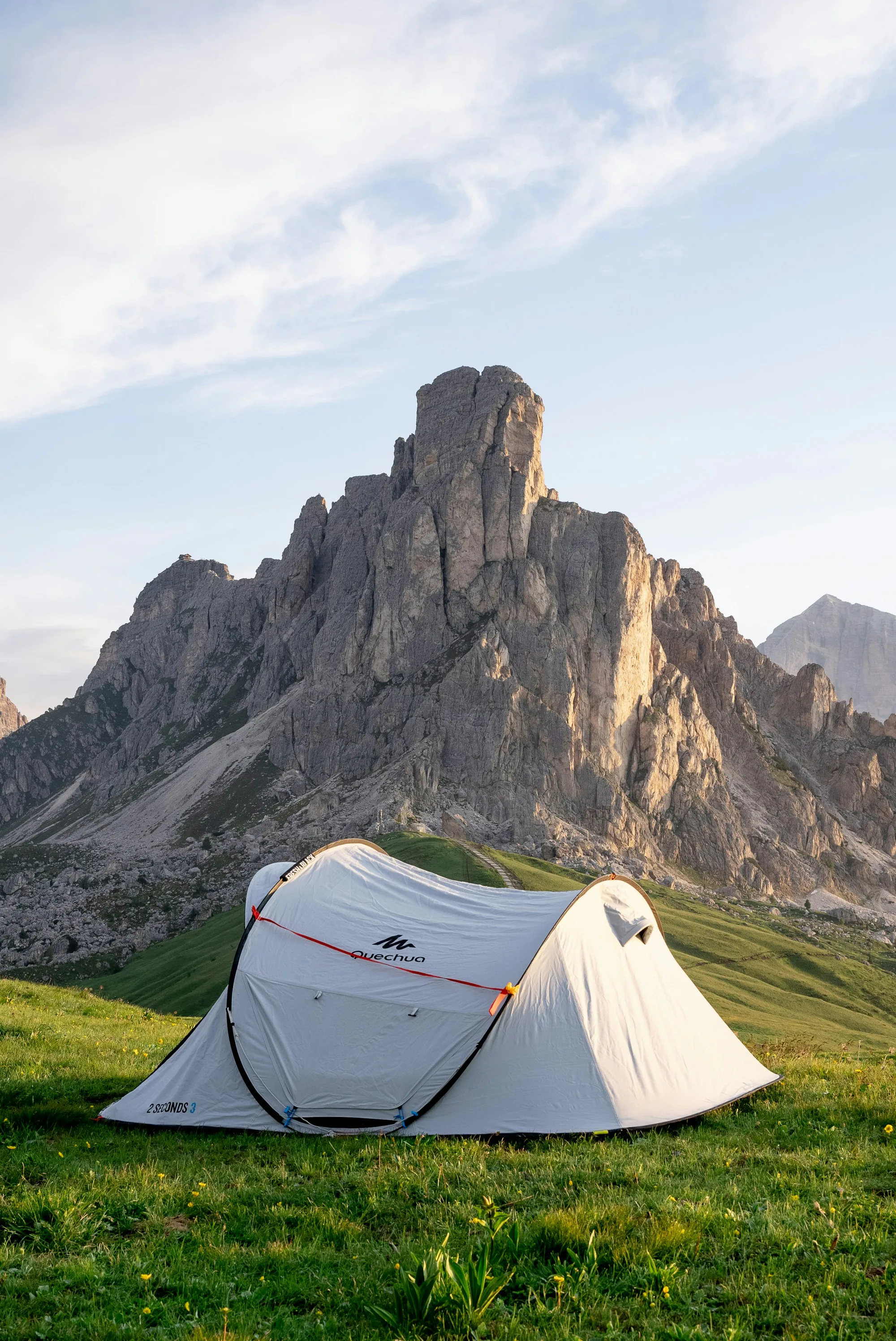 A white tent below a jagged rocky mountain