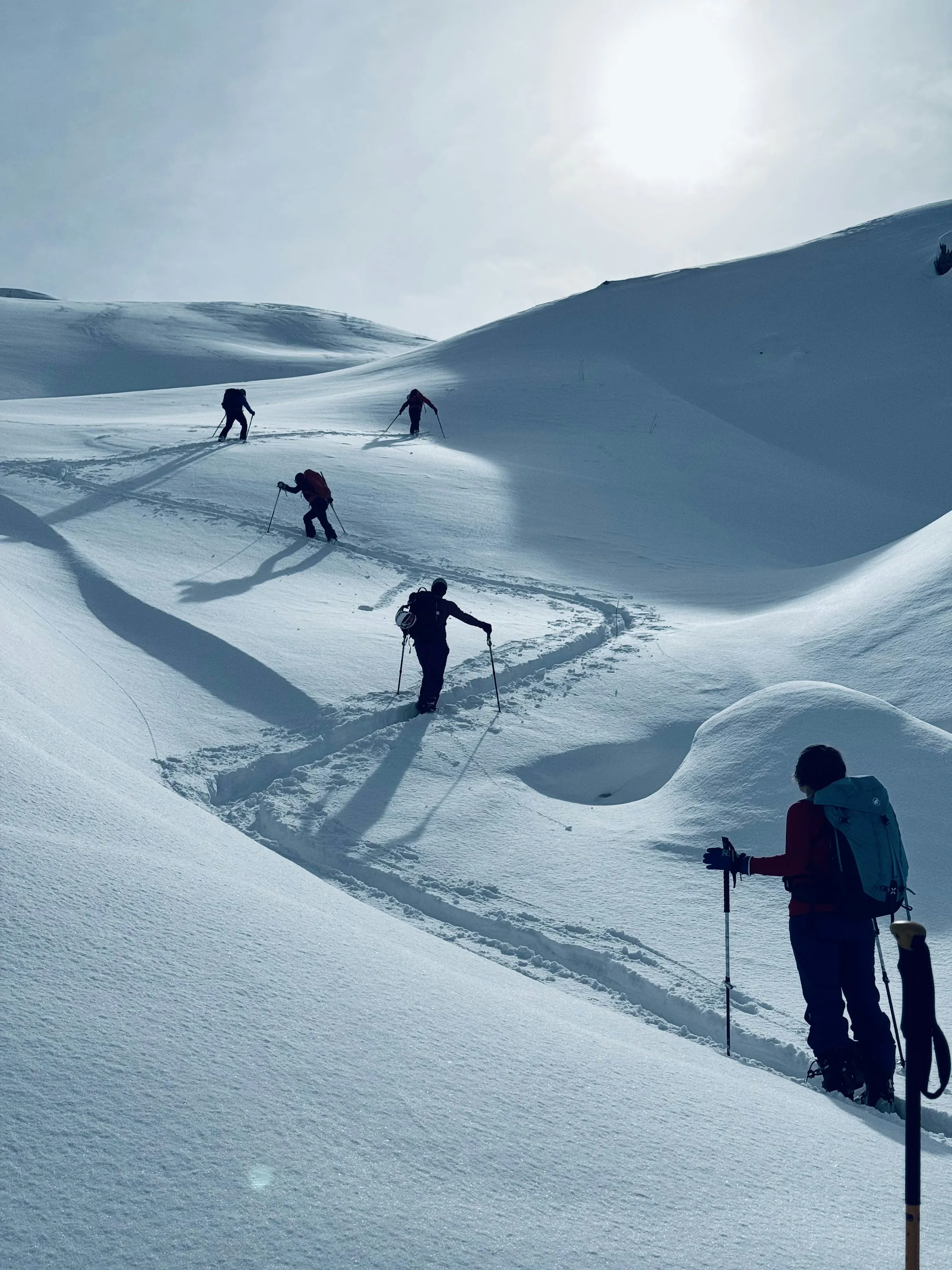 Skiers climbing a bright, snowy slope
