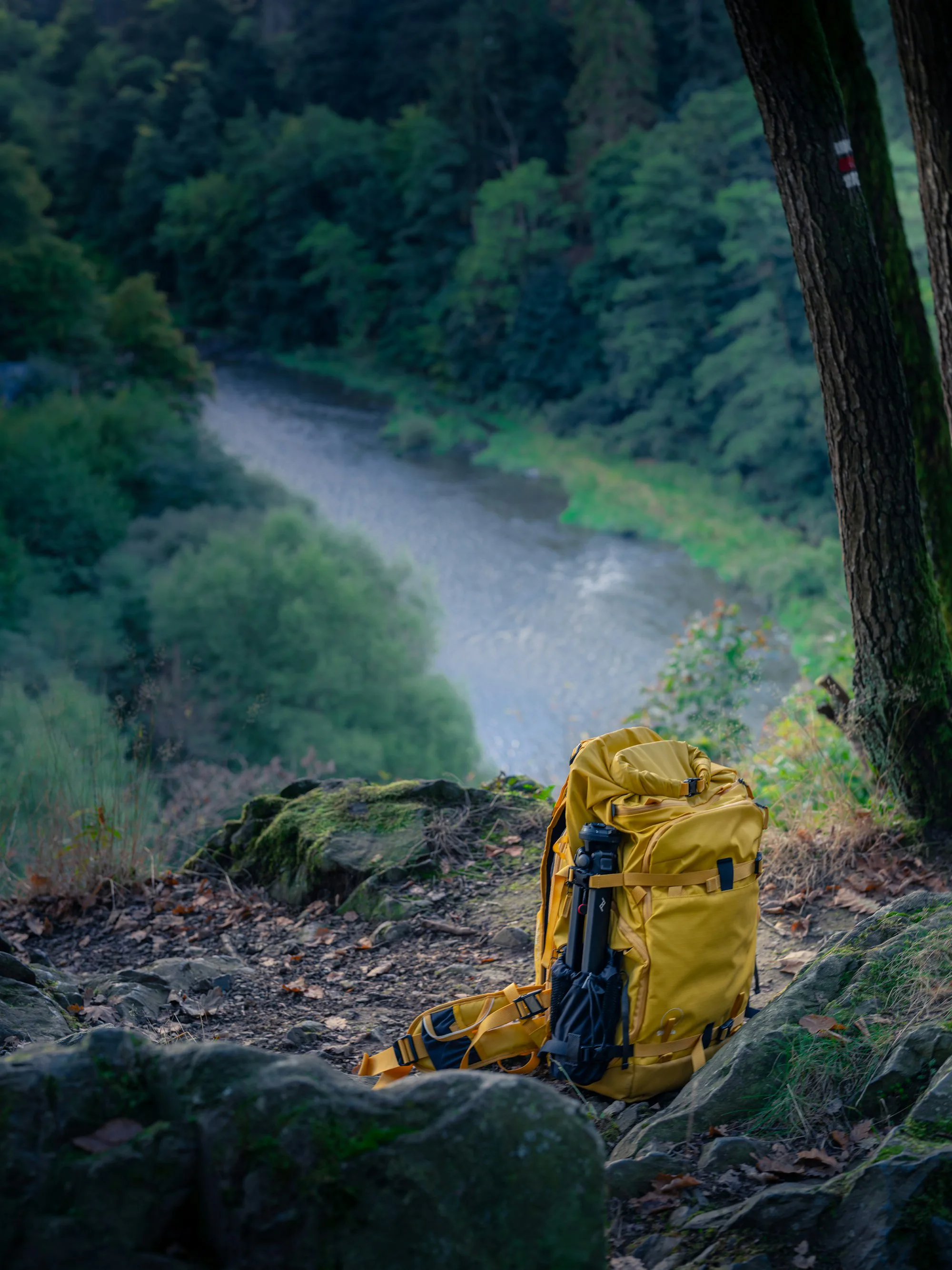 A yellow backpack on rocks above a river